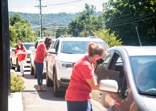 Staff members help out a line of cars waiting for Chromebooks for virtual learning students in front of Halls Elementary School in Knoxville, Tenn., on Tuesday, Aug. 18, 2020. 