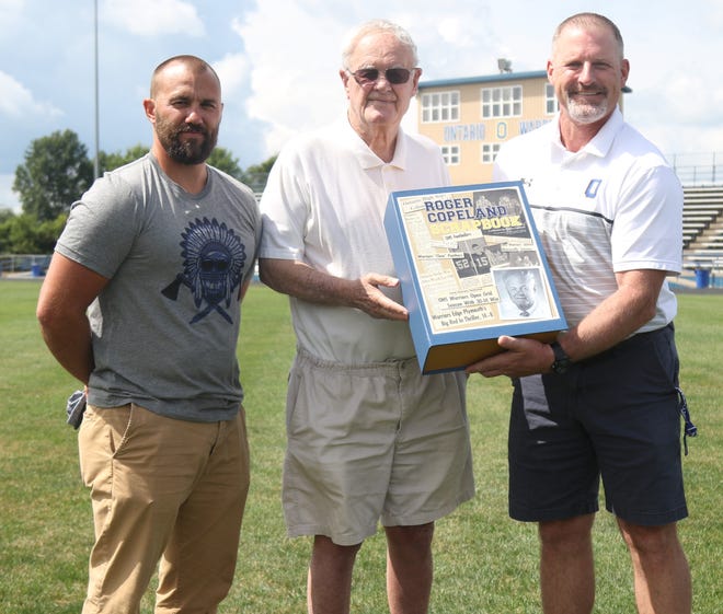 Legendary head coach Roger Copeland, middle, was presented a scrapbook by Ontario Athletic Director Jeff Fisher, right, and current head football coach Chris Miller that contains more than 900 newspaper clippings. The scrapbook was donated by the Copeland Family and it will sit in the trophy case at Ontario High School.