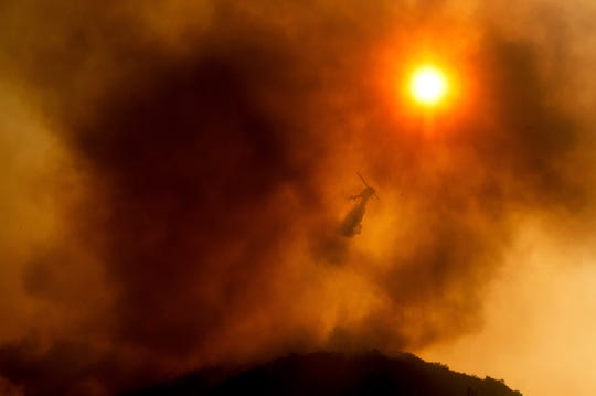 A helicopter drops water Aug. 17 at the River Fire near Salinas, one of 29 wildfires amid searing temperatures in California.