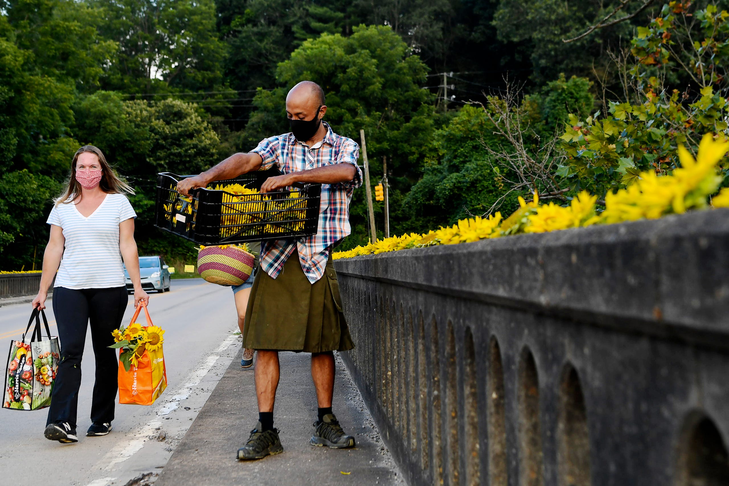 Hans Banzer lines Craggy Bridge with sunflowers in Woodfin as Sarah Pica carries more flowers to the scene August 19, 2020.