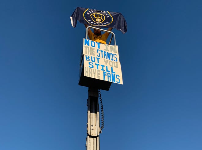 Peter Zlebek holds his Brewers flag atop a 25-foot lift where he could see the Twins-Brewers game Tuesday.