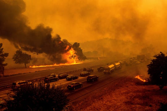 Flames from the LNU Lightning Complex fires jump Interstate 80 in Vacaville, Calif., Wednesday, Aug. 19, 2020. The highway was closed in both directions shortly afterward. Fire crews across the region scrambled to contain dozens of wildfires sparked by lightning strikes as a statewide heat wave continues.