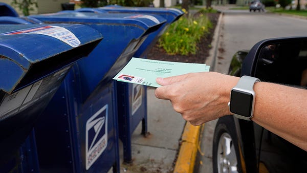 A person drops applications for mail-in-ballots in
