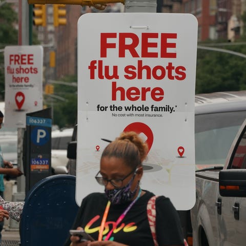 People walk past free flu shot advertisements outs