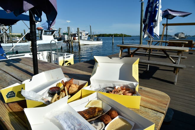 Clockwise from front: blackened grouper, conch fritters and cheese grits; mahi mahi, fried shrimp, lemon, cocktail sauce, conch fritters, french fries and coleslaw; and peel and eat shrimp at Star Fish Co. in Cortez.