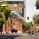 A downtown Phoenix ambassador wearing a mask during the COVID-19 pandemic rides his bicycle across the intersection of Adams street and 2nd street in Phoenix, Ariz. on July 15, 2020. 