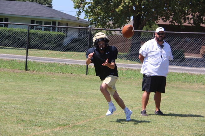 Marietta's Curry Walters hauls in a pass as head coach Alex Doby looks on during a drill.