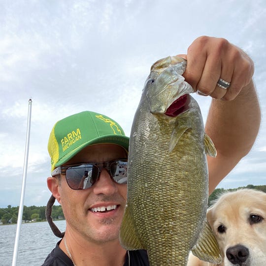 Thad Szott takes a break from selling cars to fish on Otsego Lake in Gaylord, Michigan with his dog Nicki on Saturday, August 22, 2020. He sees more and more customers shopping for vehicles to carry dogs.