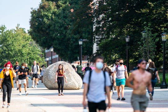 Students wearing face masks walk along the T. Anne Cleary Walkway during the first day of in-person classes at the University of Iowa.