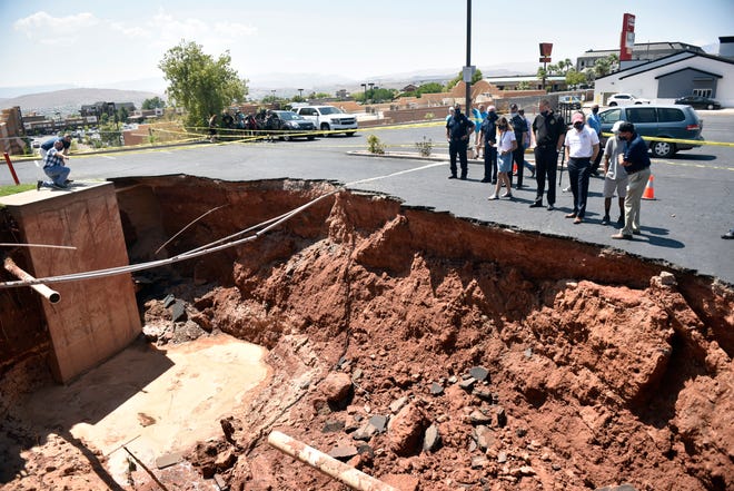 Gov. Gary Herbert and St. George Mayor Jon Pike in front of a sinkhole that opened in the parking lot of the Ramada by Wyndham hotel during a monsoon on Aug. 23, 2020. 