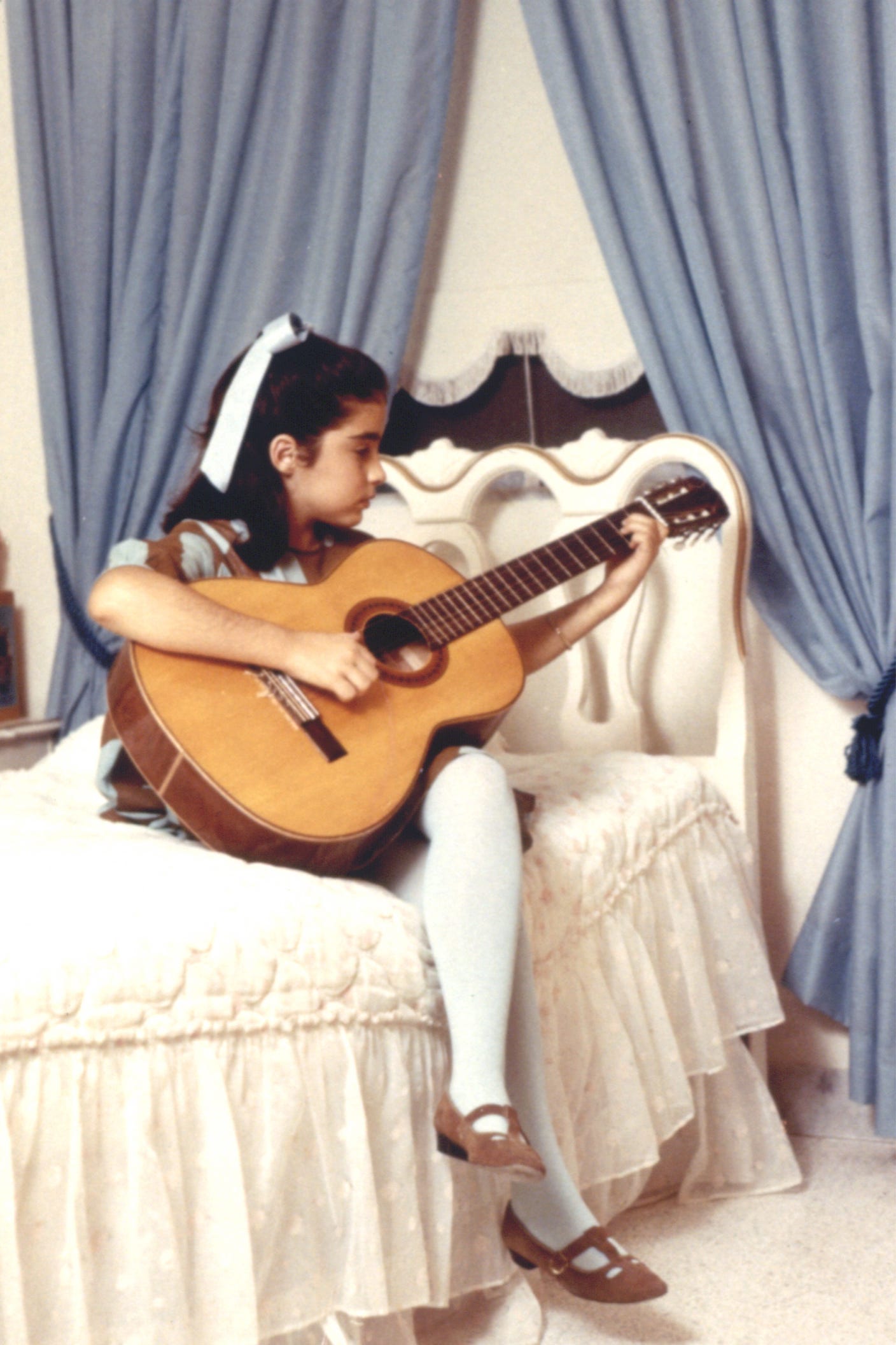 A young Gloria Estefan plays her guitar.