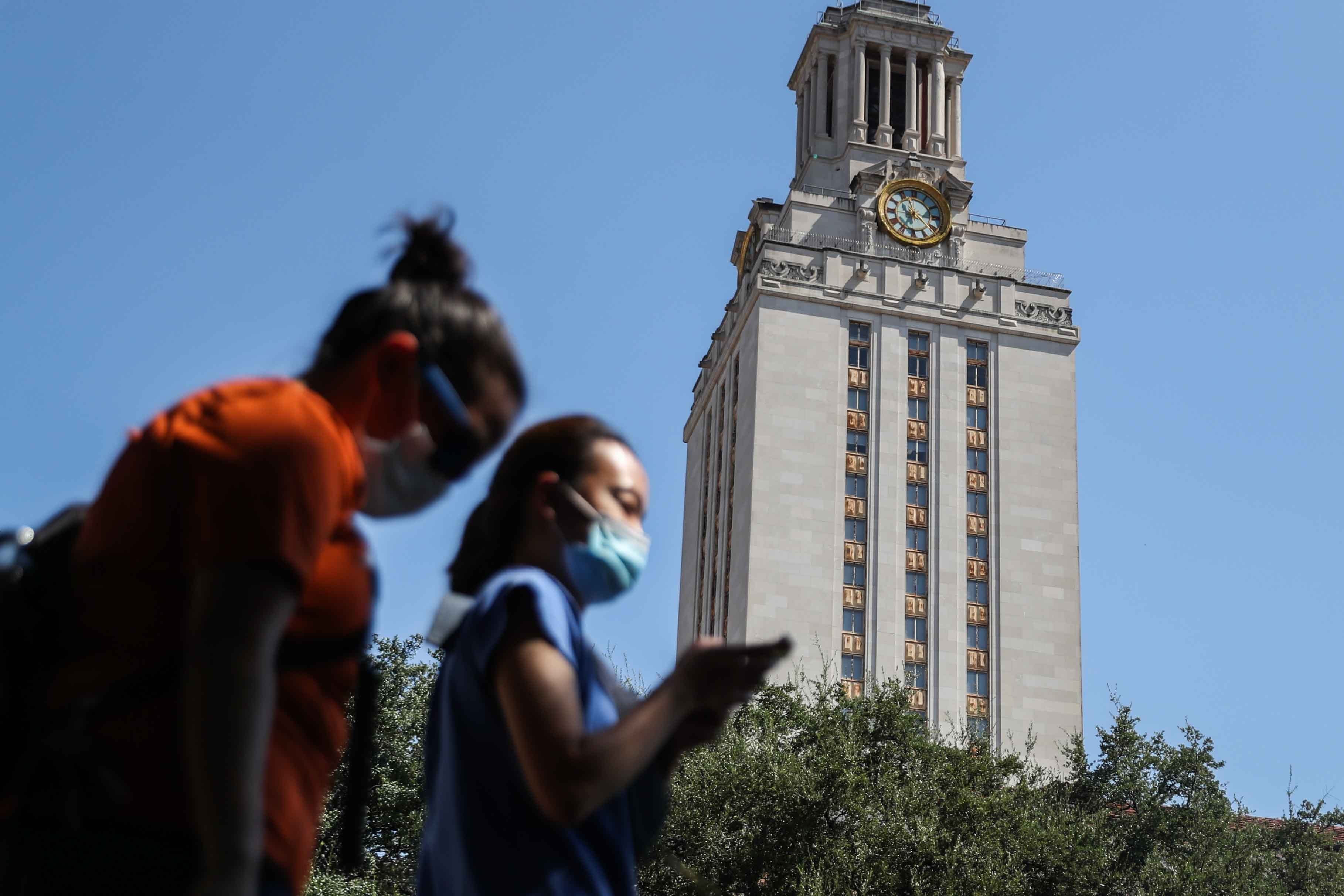 People wear masks as they pass in front of the UT Tower in Austin on Friday, August 21, 2020. 