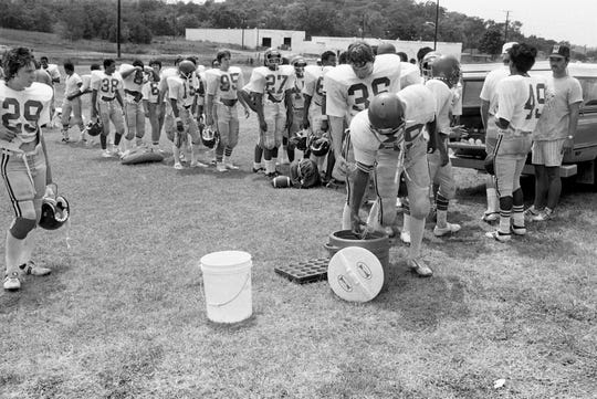A horde of Maplewood High players lineup for the Gatorade after the second practice session of the day in the over 90-degree heat Aug. 12, 1980. The players admit that the icy drink after practice is their favorite part of the day.