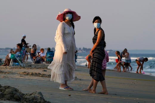 In this Aug. 11, 2020, file photo, women wear masks to help prevent the spread of coronavirus at the end of a beach day in Ogunquit, Maine.