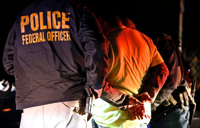 U.S. Immigration and Customs Enforcement agents detain a person during a raid.
