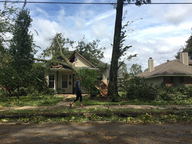 A woman walks past a damaged house on Jackson Street Thursday morning after Hurricane Laura cleared Rapides Parish.