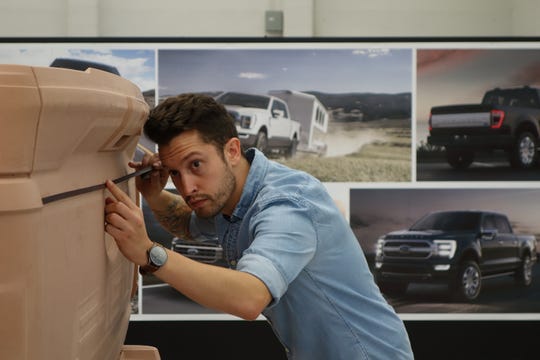 Ford senior designer Josh Henry is creating a character line with tape on the 2021 F-150 clay model. A character line is a subtle curve or indentation that gives the vehicle a unique shape and may not be noticed by the average consumer. This image was taken in 2018.