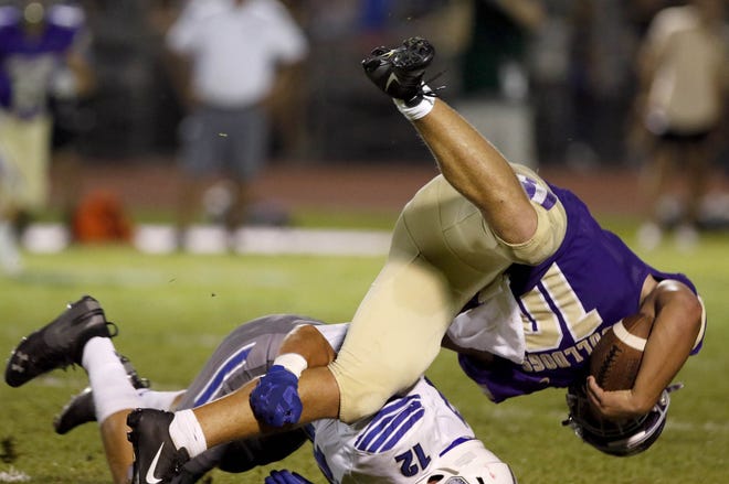 Queen Creek's Trey Reynolds (10) get upended by Chandler's Hank Pepper (12) during the first half of their game in Queen Creek. (Darryl Webb/For the Republic)