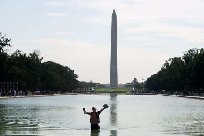 A man wades in the reflecting pool as he approaches the Lincoln Memorial.