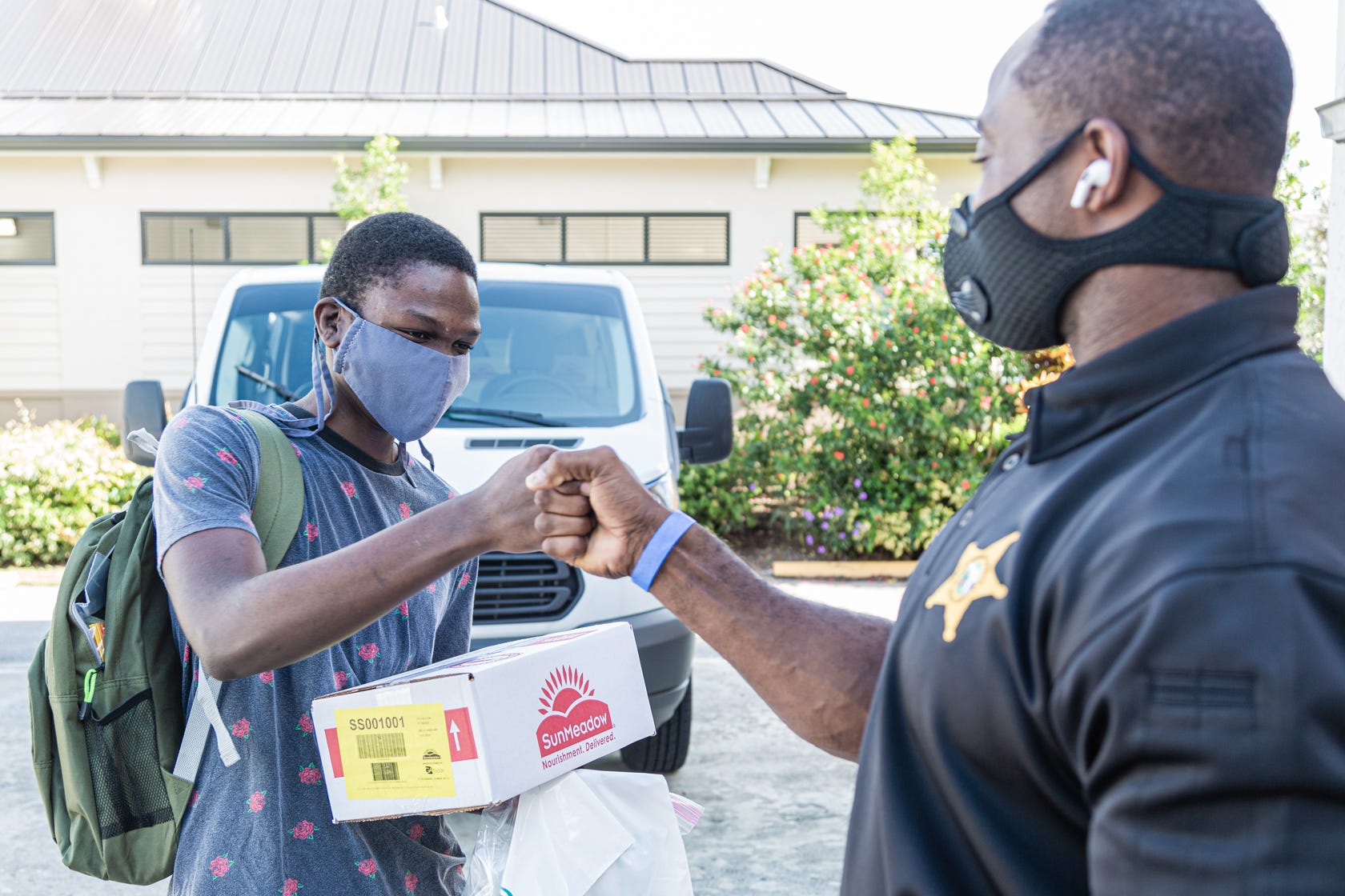 Clark Merilien, 17, who attends William T. Dwyer High School, fist-bumps Palm Beach County Sheriff’s Deputy Anthony Dukes after receiving a backpack of school supplies and a box of non-perishable food at the Colony Youth Center in Palm Beach Gardens, last August.