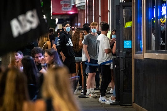 People wait in line along South University Avenue in Ann Arbor, Mich on Aug. 28, 2020.