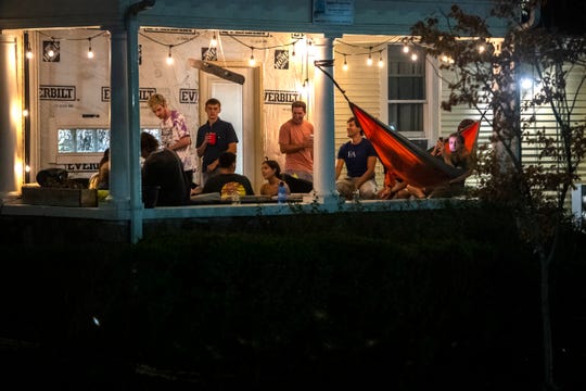 People hang out on a porch in Ann Arbor, Mich on Aug. 28, 2020.