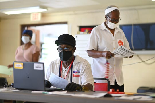 Precinct 282 poll workers Johnnie Wilford, right, and Stan Edwards register Detroit voters at Calvary Presbyterian Church  on Tuesday, Aug.  4, 2020.