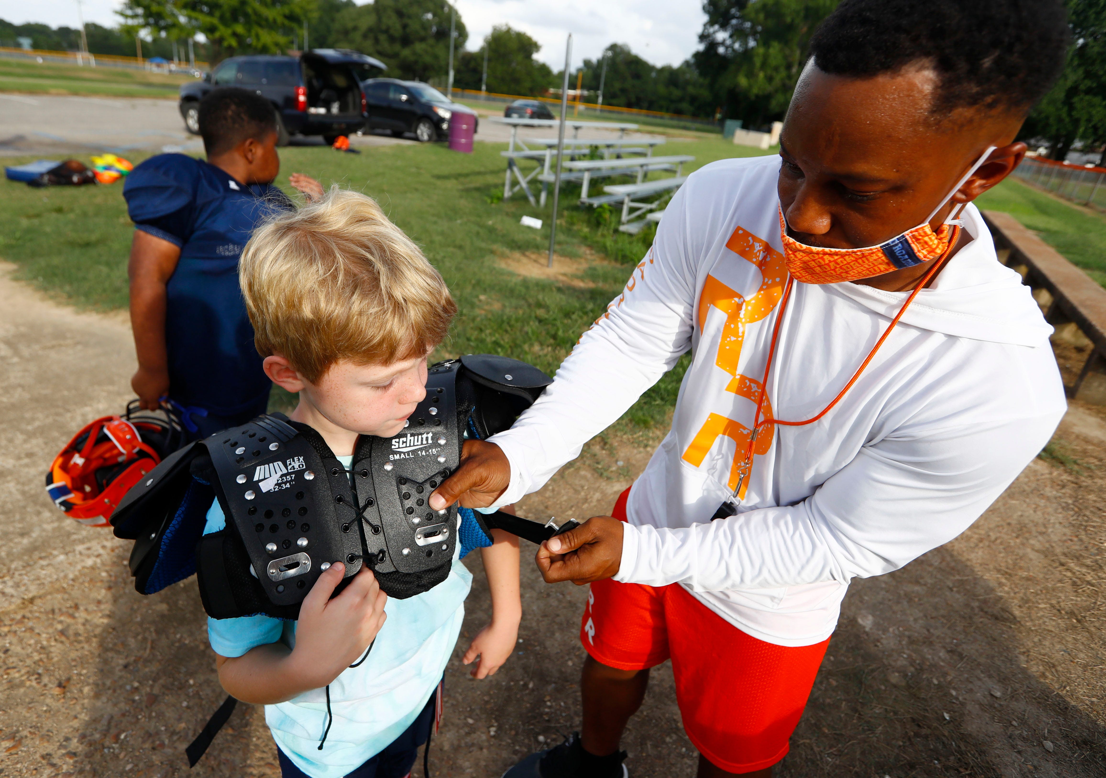 Coach Antoine Smith helps Porter Throckmorton, 8, with his pads before practice at Willow Park on Tuesday, Sept. 1 with the Mount Moriah Road Runners, a youth program created by the Sheriff’s & Police Activities League of Memphis and Shelby County, a non-profit mentoring organization.