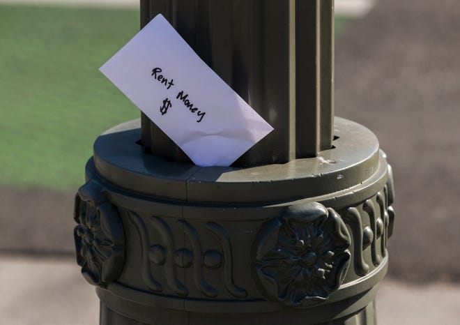 File - A paper envelope was written with the words "Rent Money $" is left tucked in a lighting pole in the Boyle Heights east district of the city of Los Angeles, Wednesday, April 1, 2020.  Gov. Gavin Newsom on Monday, Sept. 1, 2020 signed a relief bill that protects Californians, who haven't paid their rent since March 1 because of the coronavirus, from being evicted through at least Jan. 31, 2021.