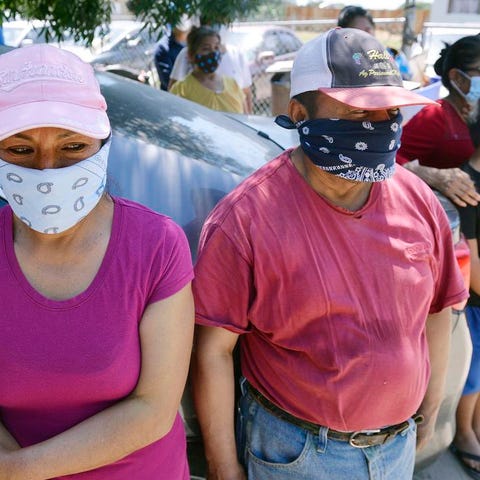 Farm workers and their families wait for donated f