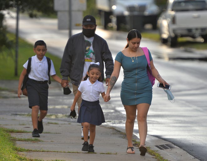 Juliette Salgado, 5, walks with her mom, Yovani, to Samoset Elementary for her first day of kindergarten. Behind them, Samoset fourth grader Viviano Alvarado Jr., 9, walks with his dad, Viviano, on the first day of classes for students in Manatee County last month.