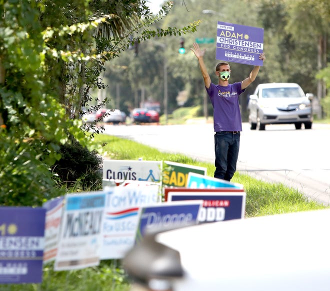 Adam Christensen, a candidate for U.S. Congress in Florida's Third Congressional District, waves to motorists as he campaigns Aug. 18 outside the Millhopper Branch Library in Gainesville.