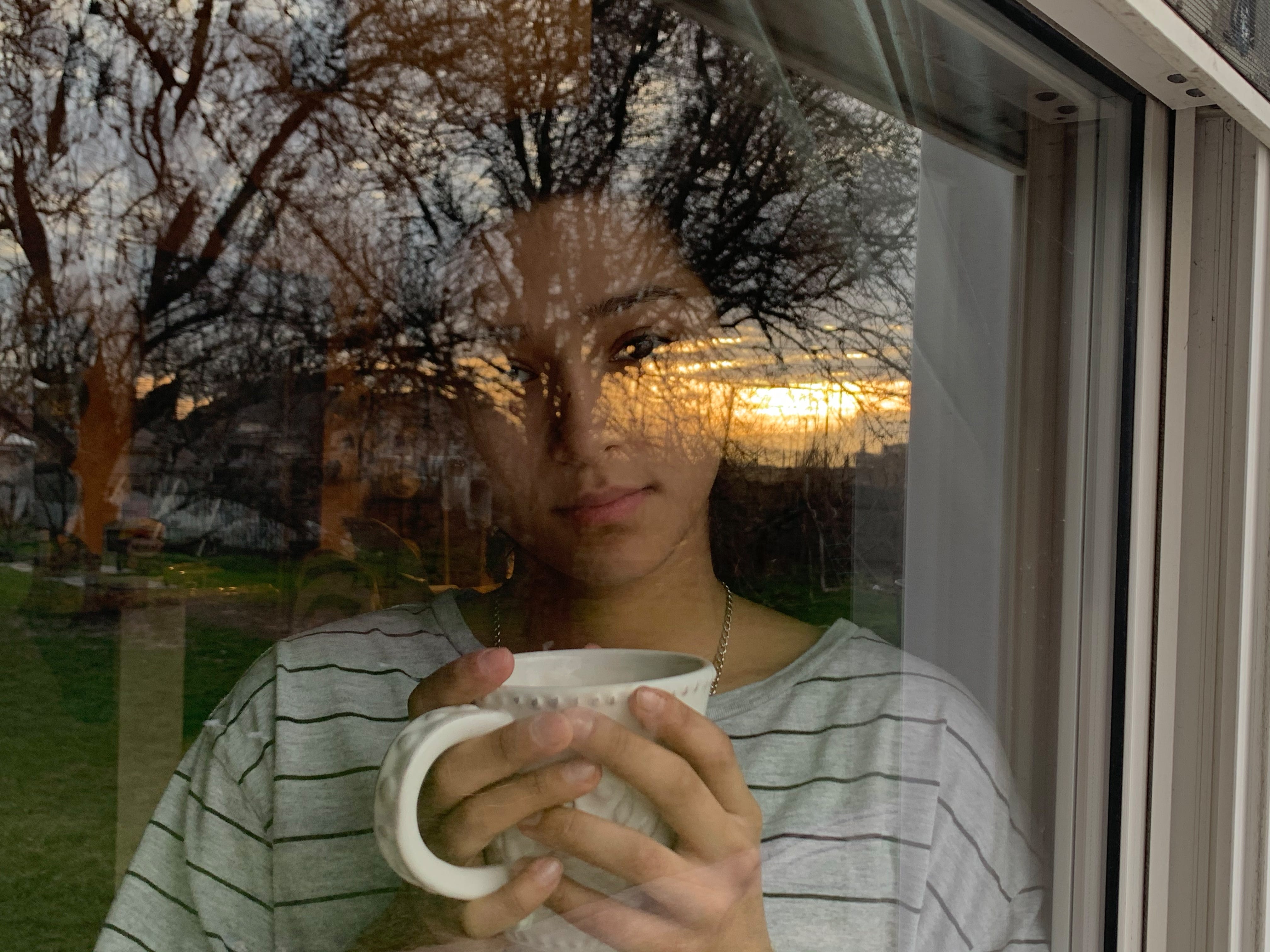 My sister Cassandra Ruiz, 17, looks out a window in our home during sunrise in Detroit on April 6, 2020. At times my sister and I have difficulties communicating and understanding each other. To me this image represents that no matter how different someone is from you, at the end of the day you have to see through them and realize that everyone shines in their own way.

