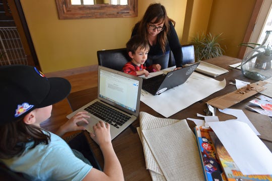 Emily Love helps her 7-year-old son Foster, a first grader at Pioneer Elementary School in Lafayette, with his work on March 31, 2020, the first day all students in the Boulder Valley School District migrated to online learning during the coronavirus shut down. His older brother, Miles, 12, is working in a Google chat room on a physical science problem with one of his 6th grade classmates from Manhattan Middle School in Boulder.