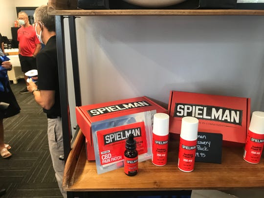 Former Ohio State and Detroit Lion Chris Spielman stands in the background (in red) of a new CBD venture opening in Granville. One of the products, a roll-on, is marketed under the name Spielman.