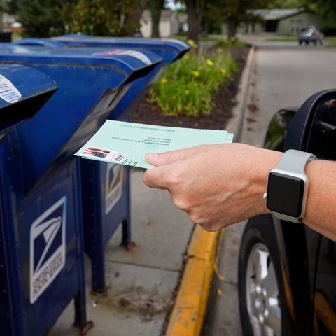 A person drops applications for mail-in-ballots in