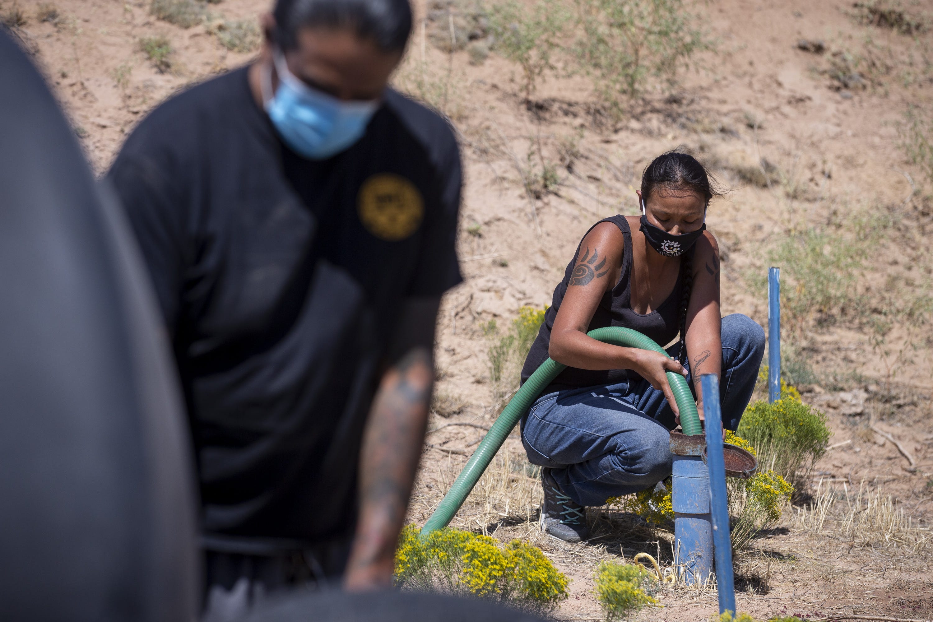Deborah Tso pours water into a family's underground tank on Sept. 1, 2020, in Steamboat, Ariz. Water Warriors United delivers water to families in need all across the Navajo Nation.