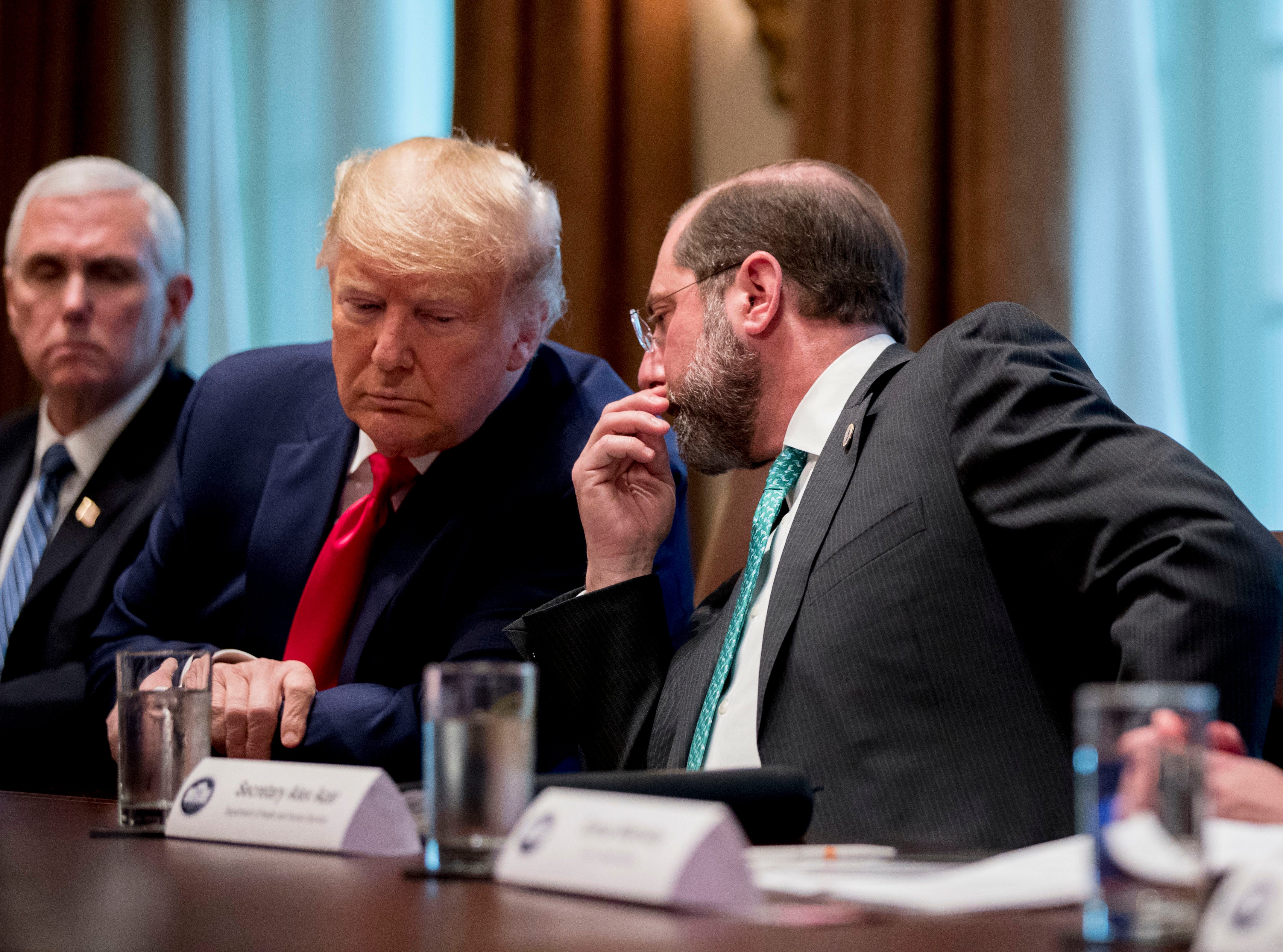 Health and Human Services Secretary Alex Azar, center, accompanied by Vice President Mike Pence, left, whispers with President Donald Trump, during a meeting with pharmaceutical executives on the coronavirus.