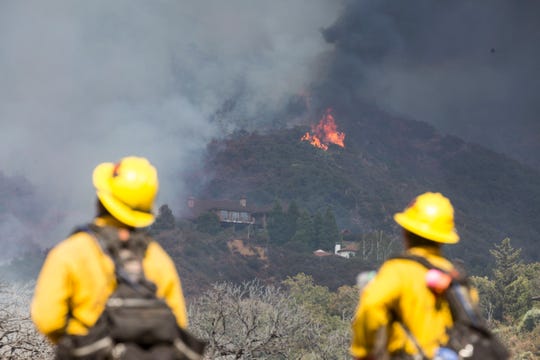 Firefighter watch as a wildfire burns at a hillside behind homes in Yucaipa, Calif., Saturday, Sept. 5, 2020. (AP Photo/Ringo H.W. Chiu)