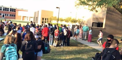 Masked Pratt students gather outside Liberty Middle School before entering each morning for school.