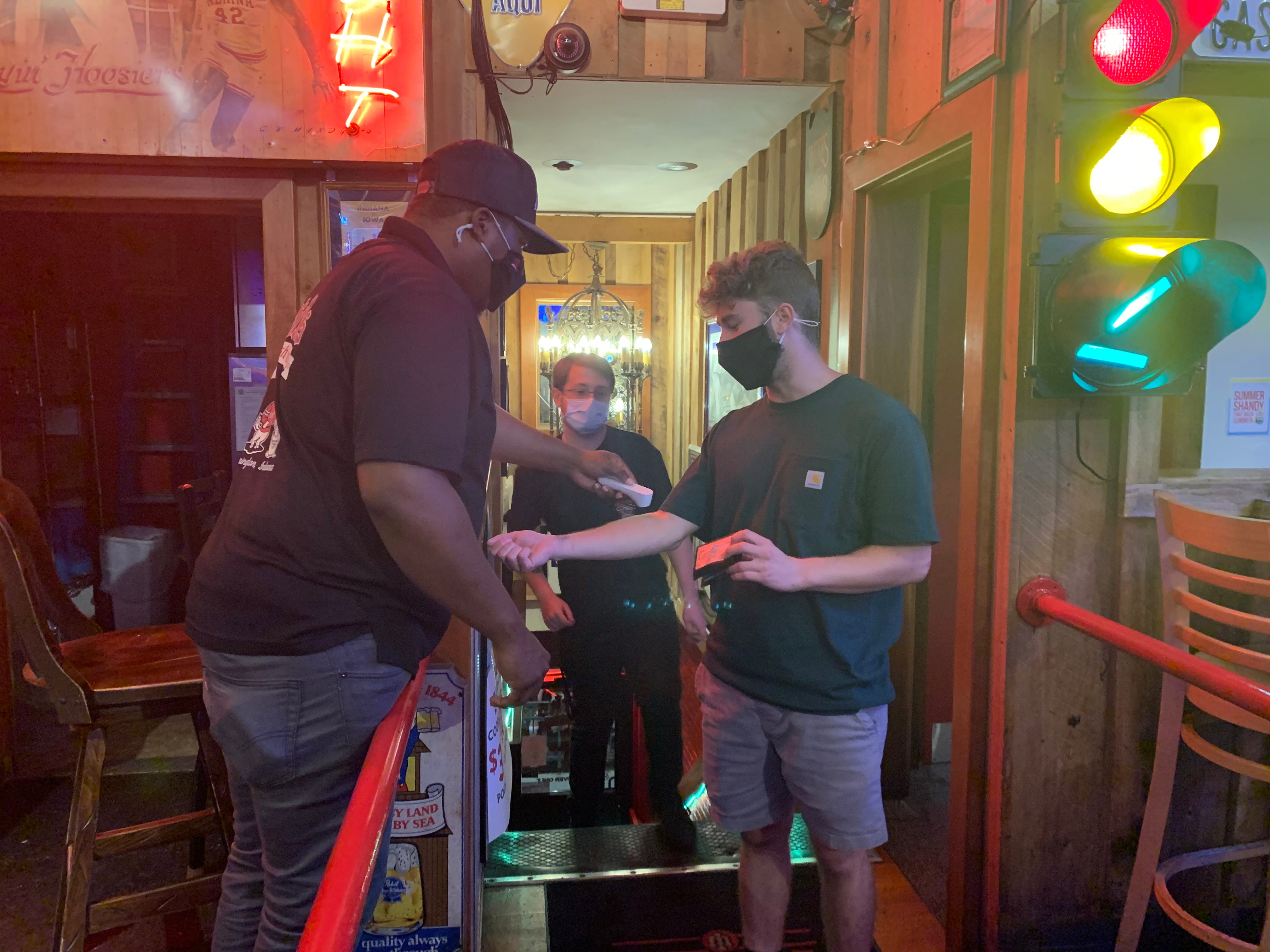A bouncer tends to a patron entering Nick's bar near the Indiana University campus on Thursday.