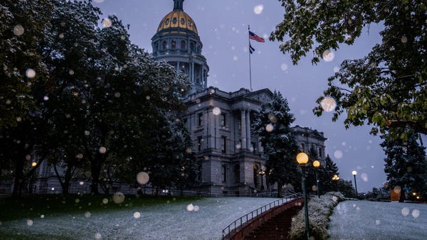 Snow falls outside the Colorado State Capitol buil