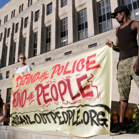 Protesters hold a banner wanting to defund police 