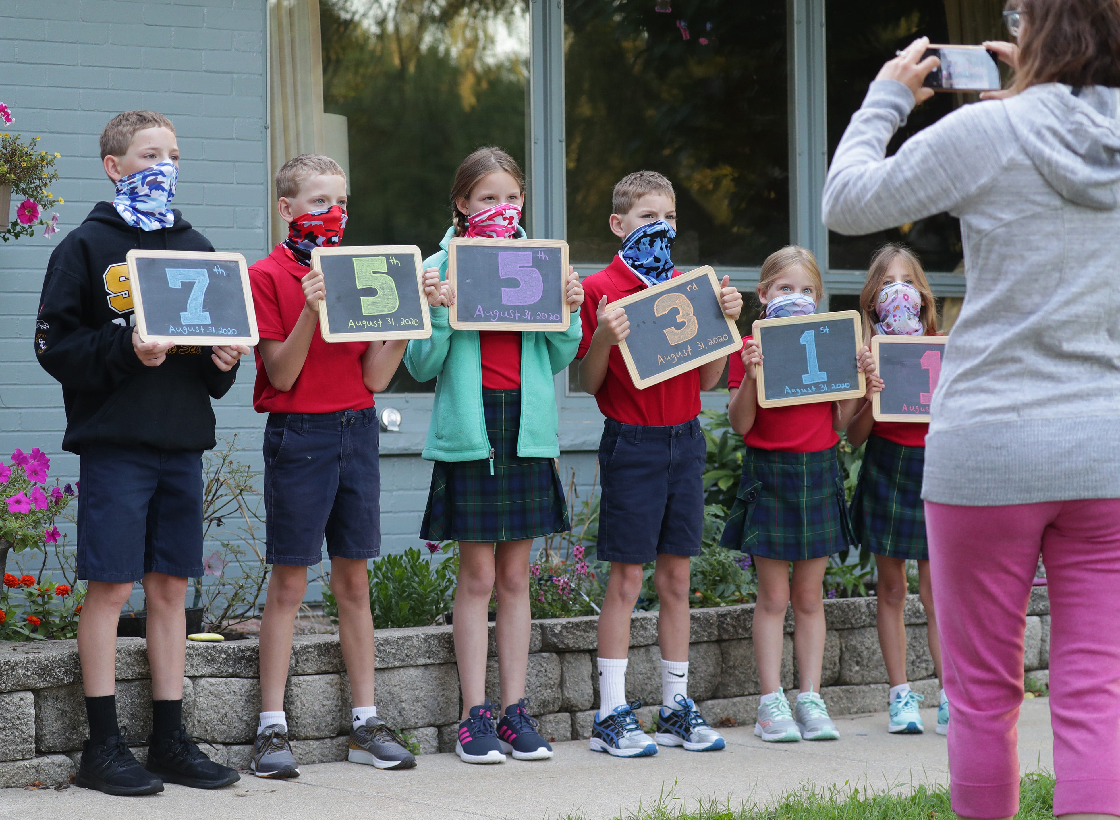 Lacey Tomczuk takes a photo of her children, all wearing masks, before they get on the bus for their first day of school in Bayside, Wis., on  Aug. 31.