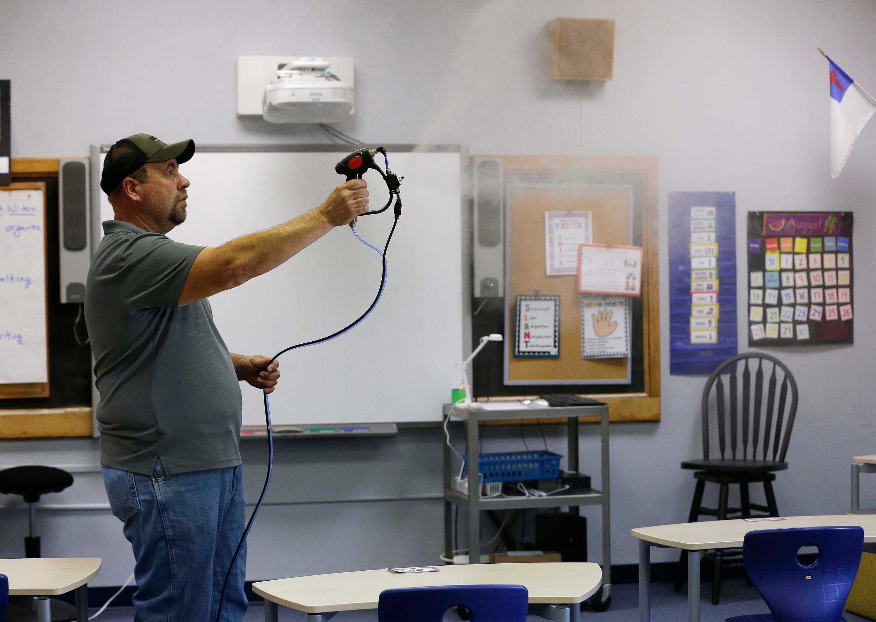 Randy Du Mez, of Ozo Kleen waves sanitizing fog in a Sheboygan Christian Elementary School classroom, Friday, August 28, 2020, in Sheboygan, Wis. The school, in addition to their safety protocols has added the fogging as an additional layer of safety for the school's 148 elementary students.