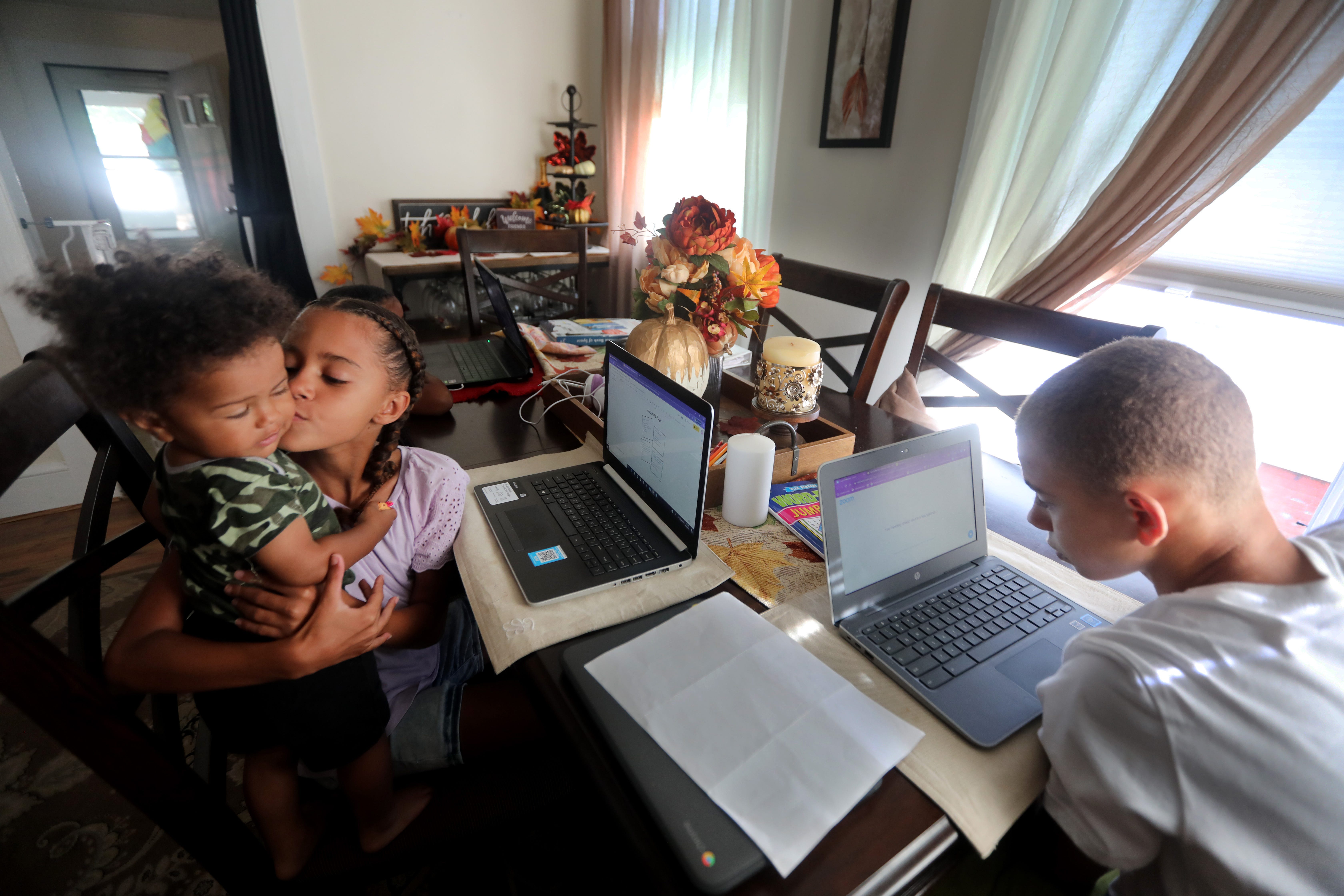 Families juggling remote learning for the first time faced a difficult learning curve. Here Leighann Jansen, 9, a fourth-grade student in Middletown, takes a moment from her work on the first day of school to kiss her 1-year old brother, Luca. There are seven people in the Jansen family, and remote learning has made multitasking essential.