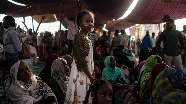 A young Sudanese girl watches protestors pass by d
