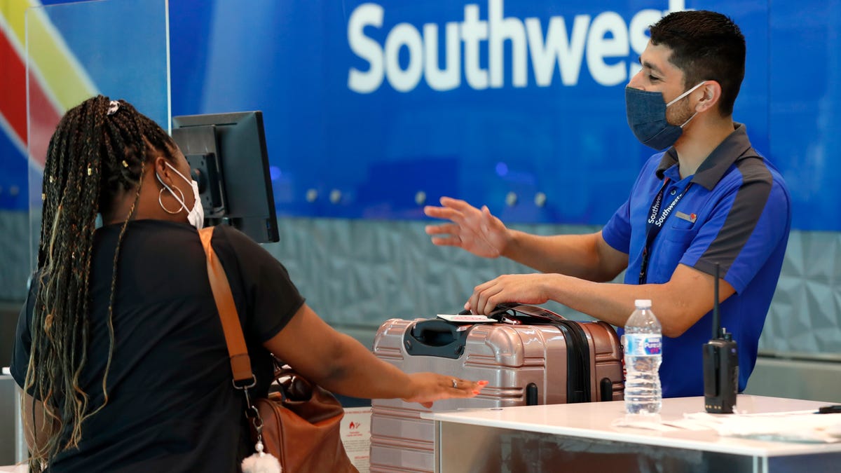 Southwest Airlines employee Oscar Gonzalez, right, assists a passenger at the ticket counter at Love Field in Dallas.