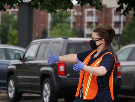 Amy Woolf, a job service career counselor for the Department of Workforce Development, directs people on July 15 at a drive-thru job fair in Oshkosh. The department is hosting a series of more job fairs using the drive-thru format on Thursday.