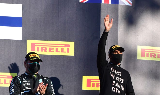 Winner of the race, Mercedes driver Lewis Hamilton of Britain, right, waves as he stands with second place Mercedes driver Valtteri Bottas of Finland on the podium during the Formula One Grand Prix of Tuscany, at the Mugello circuit in Scarperia, Italy, on Sunday.